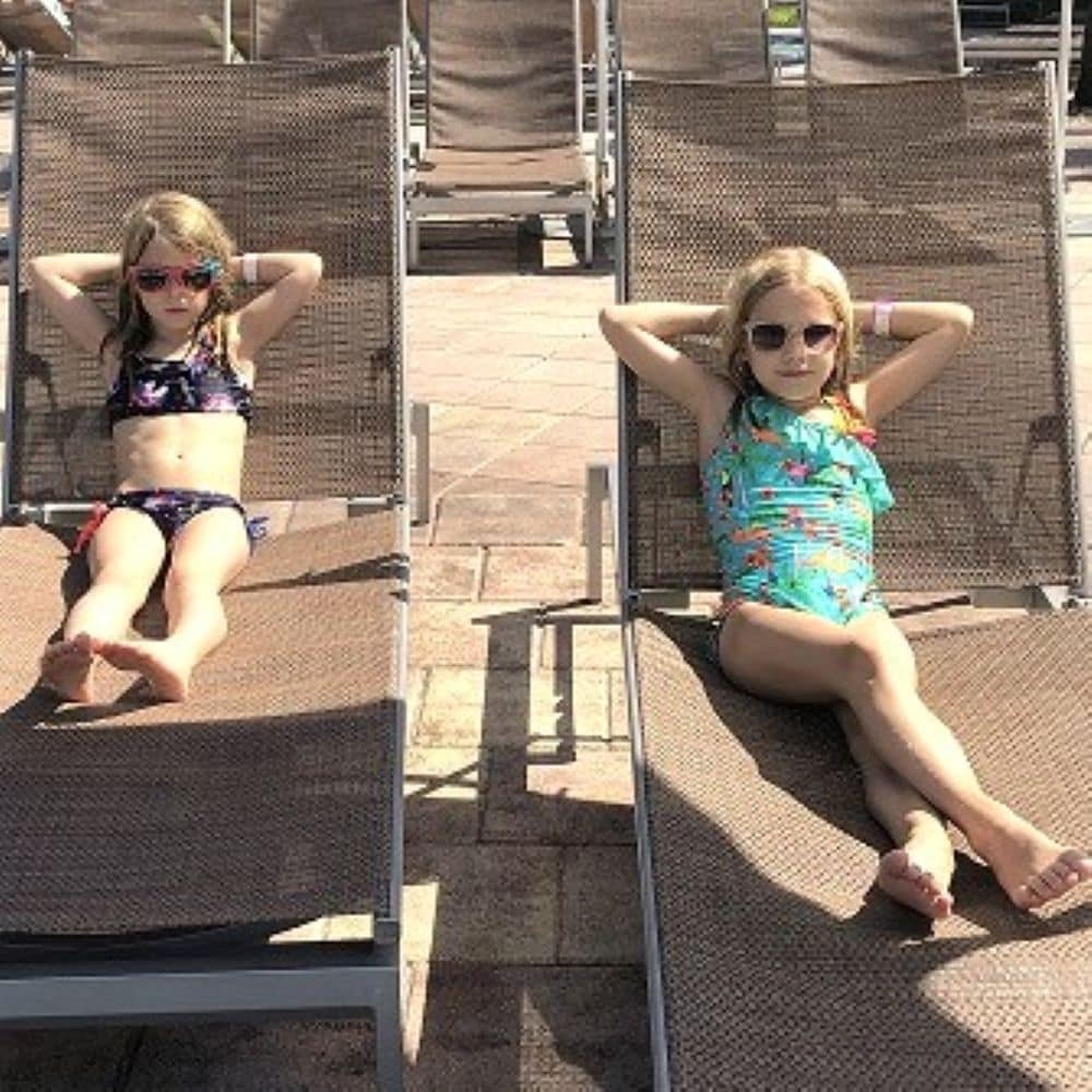 Two Little Girls on Lounge Chairs by a Pool