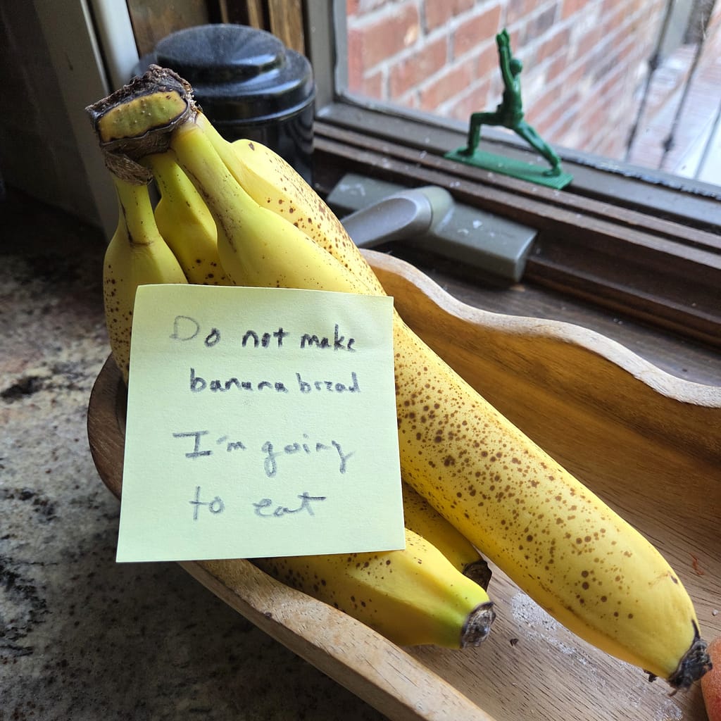 Bananas on a Counter with a Post-it Note Saying "Do Not Make Banana Bread. I am going to eat."