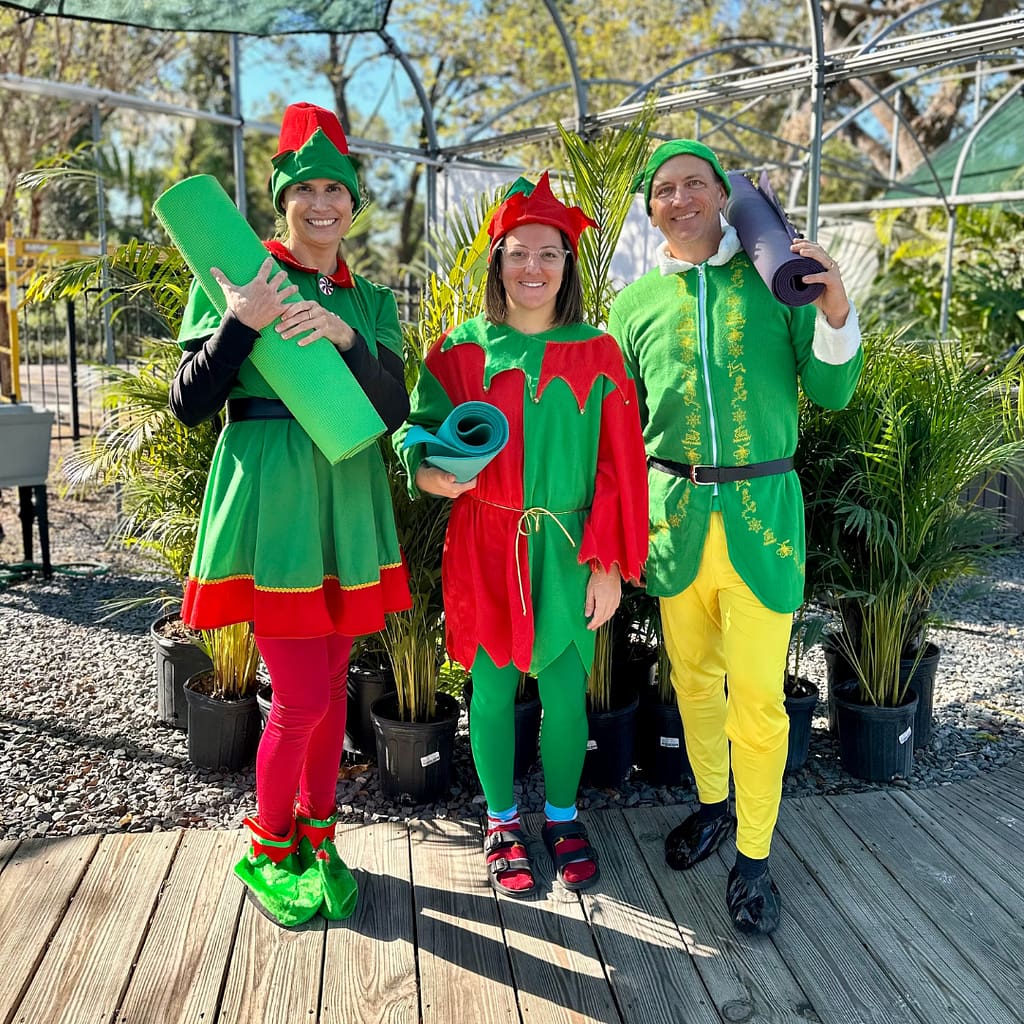 Three People Wearing Elf Costumes and Carrying Yoga Mats for Kerby's Nursery Elf Yoga in the Garden