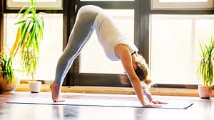 Lady Doing Yoga Downward Facing Dog Pose with Plants in Background