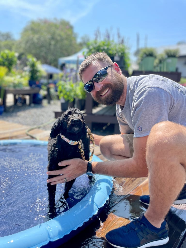 Dog in a Splash Pad with Owner Next to It