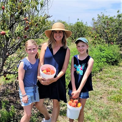 Maddy and Abby with their mom, Kim, holding peaches
