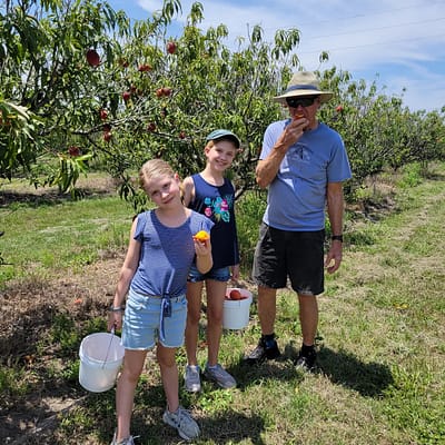 Maddy, Abby, and Papa (Larry Kerby) picking peaches
