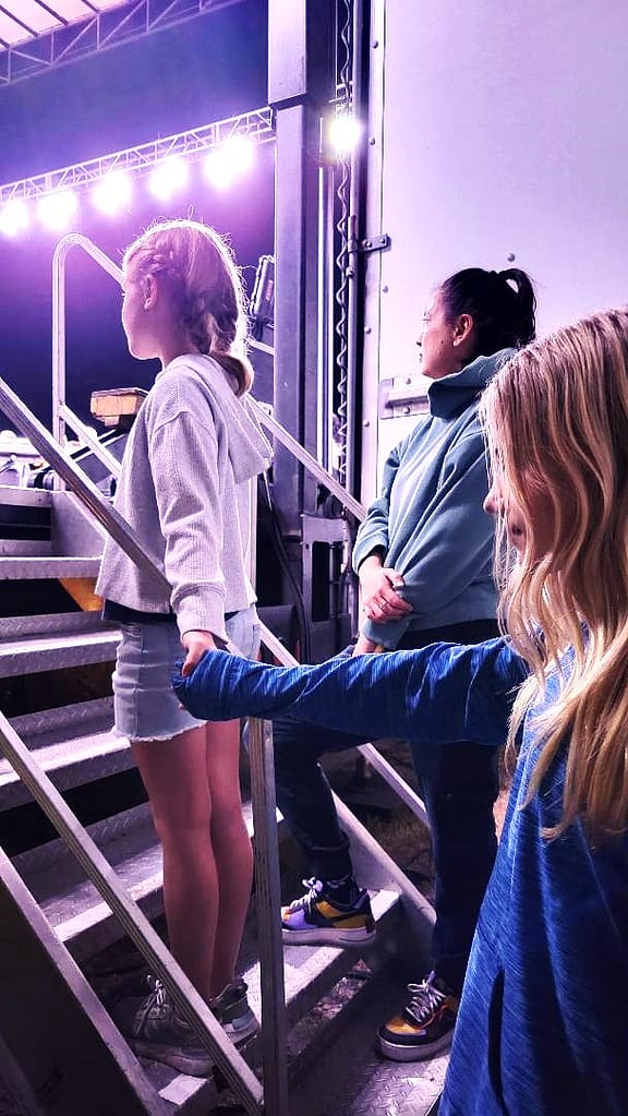 Maddy getting ready to go on stage with Abby holding her hand.